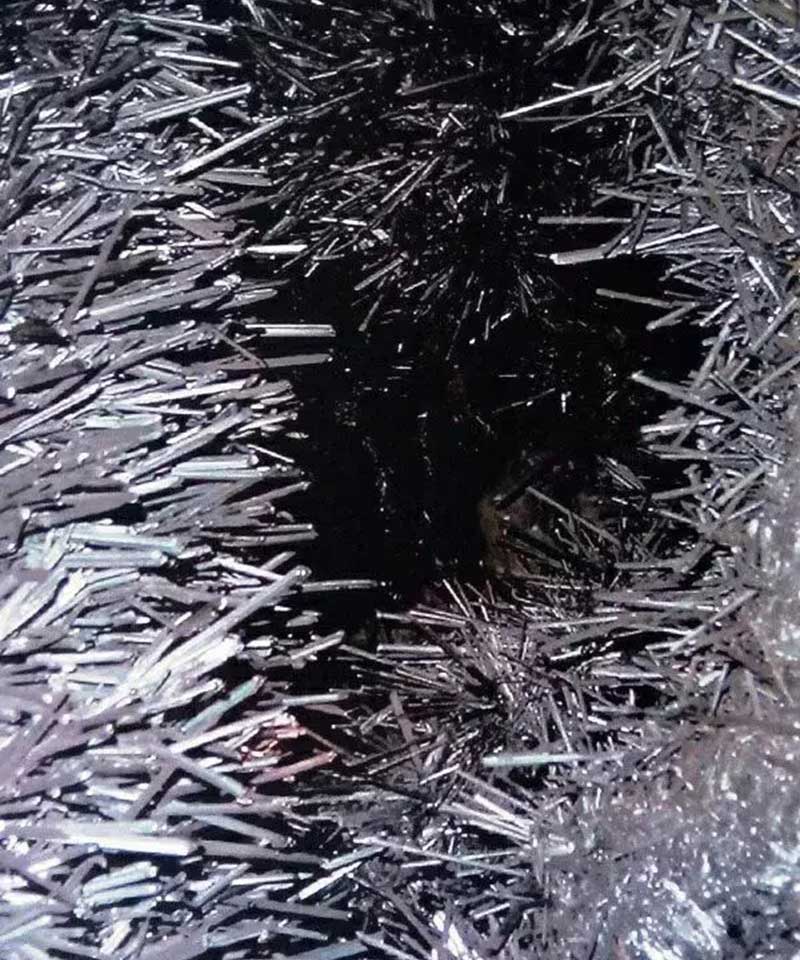 Shiny needle-like stibnite crystals forming a dense black cluster