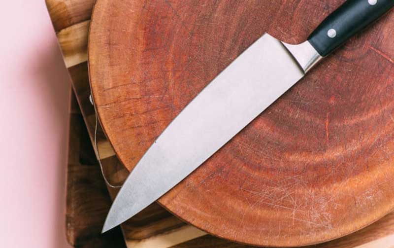 A modern chef’s knife placed on a wooden cutting board, representing the transition from stone tools to metal tools as human civilization advanced