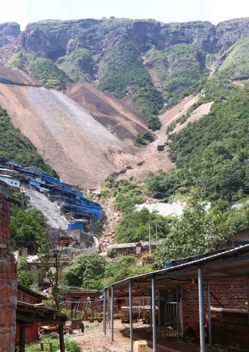 a mountainous mining site where decades of activity have carved deep scars into the slopes.