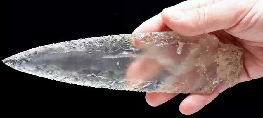 A finely crafted prehistoric stone spearhead, knapped from quartz or flint. This bifacial tool was used by early humans for hunting and cutting, showcasing ancient craftsmanship.