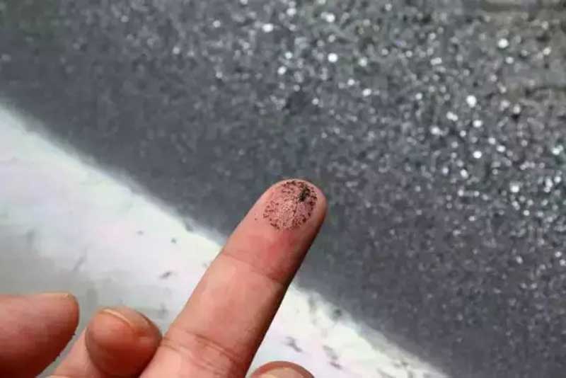 Fine tungsten concentrate collected after separation, shown on a fingertip.