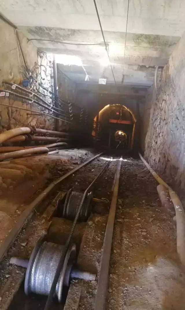 Inside a small underground copper mine, ore is hauled from several hundred meters below the surface. Winches and rail-mounted carts move the material up through the incline shaft to reach the ground level.