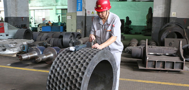 a worker is testing the hardness of roller for roll briqutter in workshop